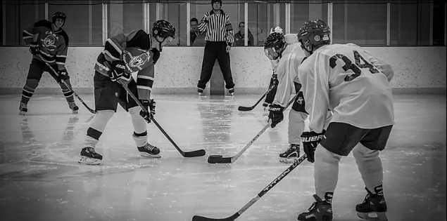Black and white photo of players lined up at centre ice for face off